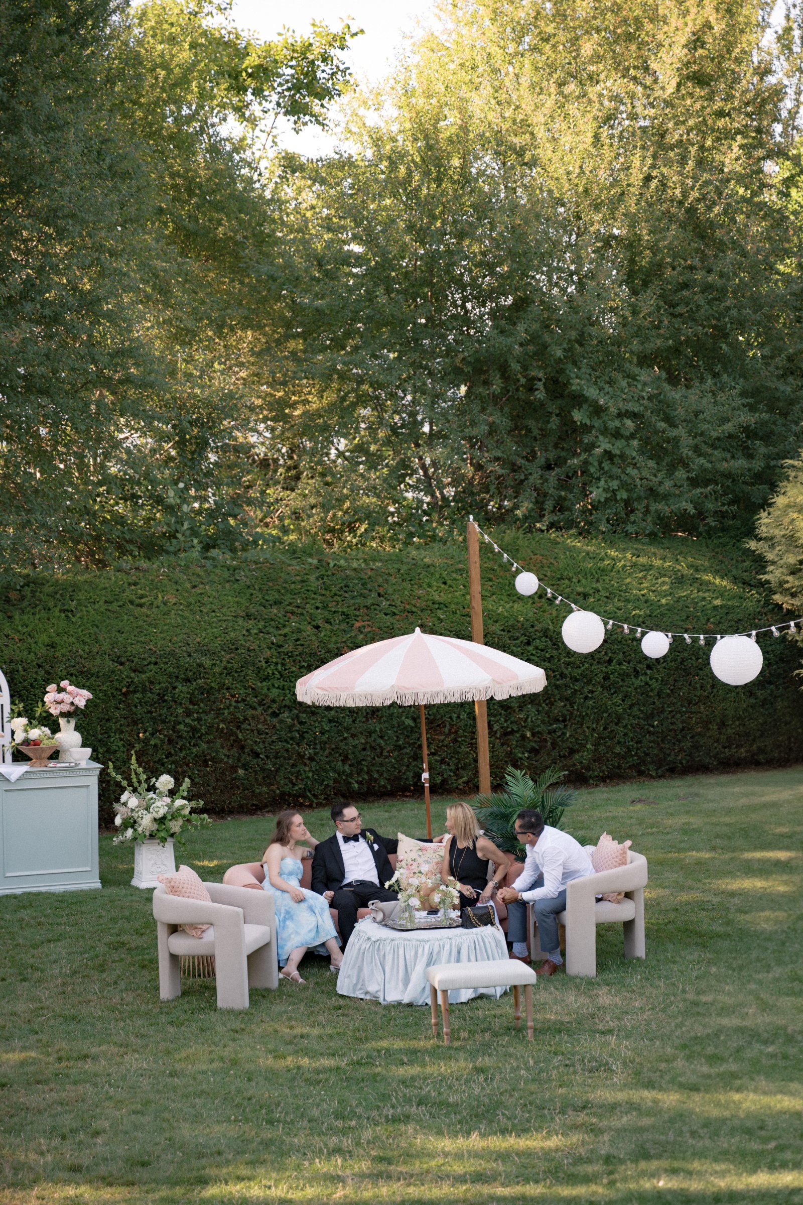 Luxury garden lounge featuring Light Sage Green Gathered Slip Cover & Ottomans with vintage furniture, umbrellas, and outdoor wedding seating