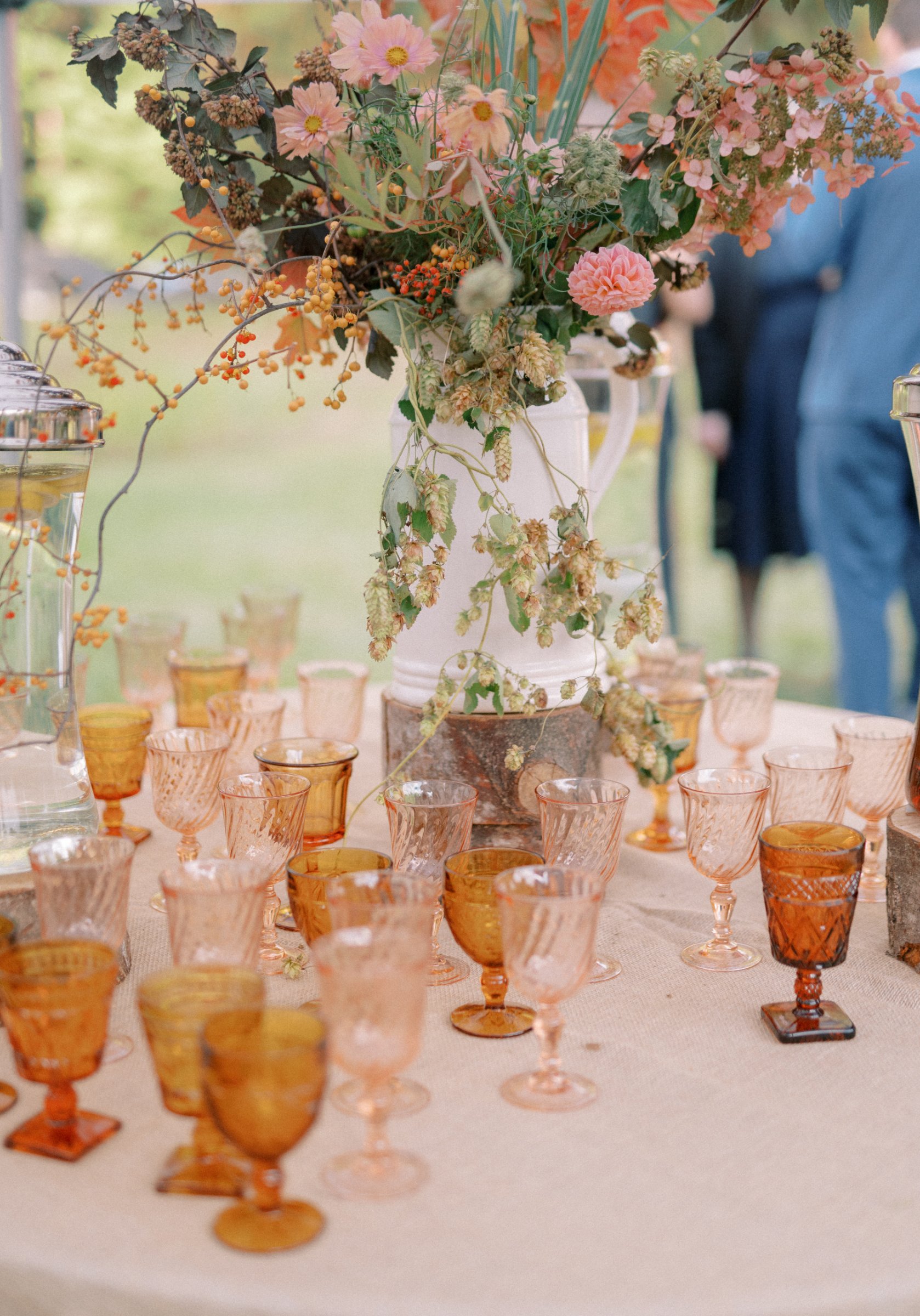 Authentic vintage amber glass goblets styled on an elegant outdoor wedding reception table with seasonal florals and layered tabletop décor.