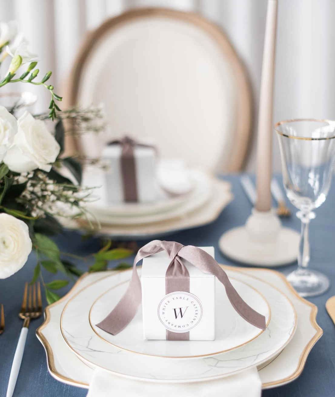 Anna Weatherly White & Gold Charger layered with fine dinnerware, custom stationery, crystal stemware, and floral accents for an elegant wedding place setting.