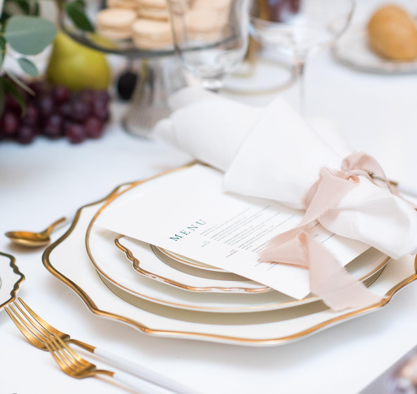 Anna Weatherly White & Gold Charger styled beneath fine dinnerware for an elegant plated wedding reception with modern table styling.