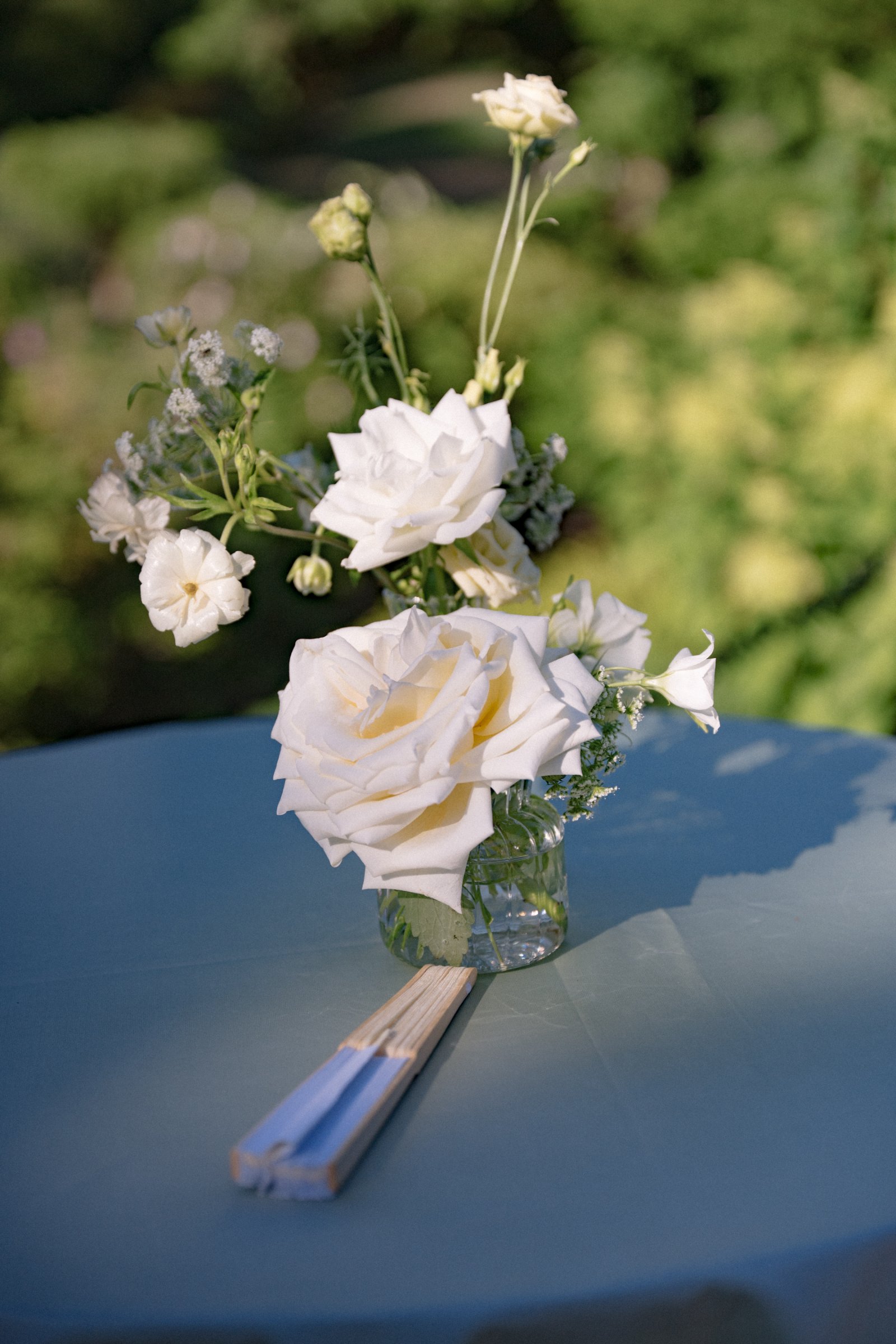 Clear glass bud vases styled with delicate white flowers on an elegant wedding cocktail table