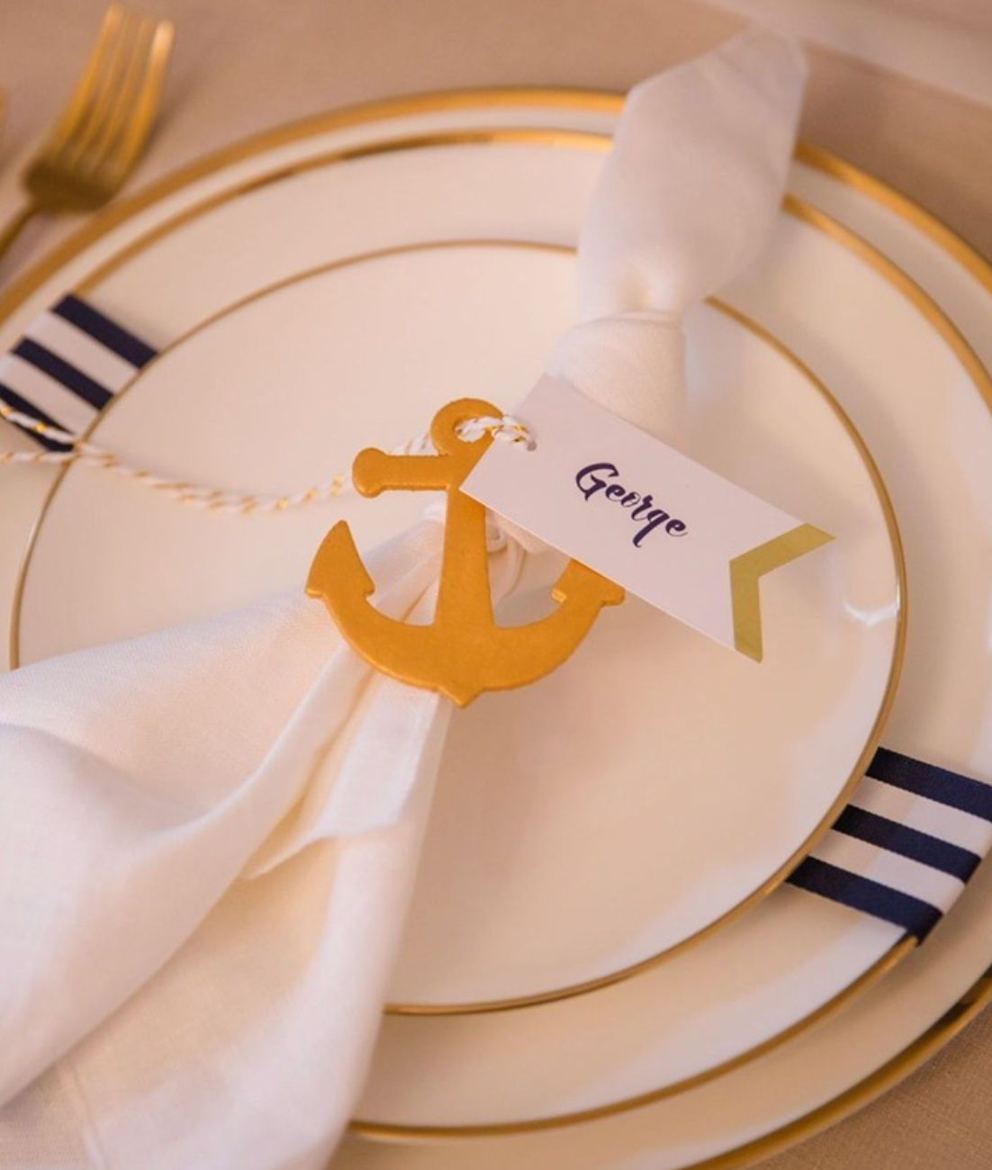 Close-up of Brushed Gold Coupe Charger layered beneath white porcelain dinnerware with gold flatware