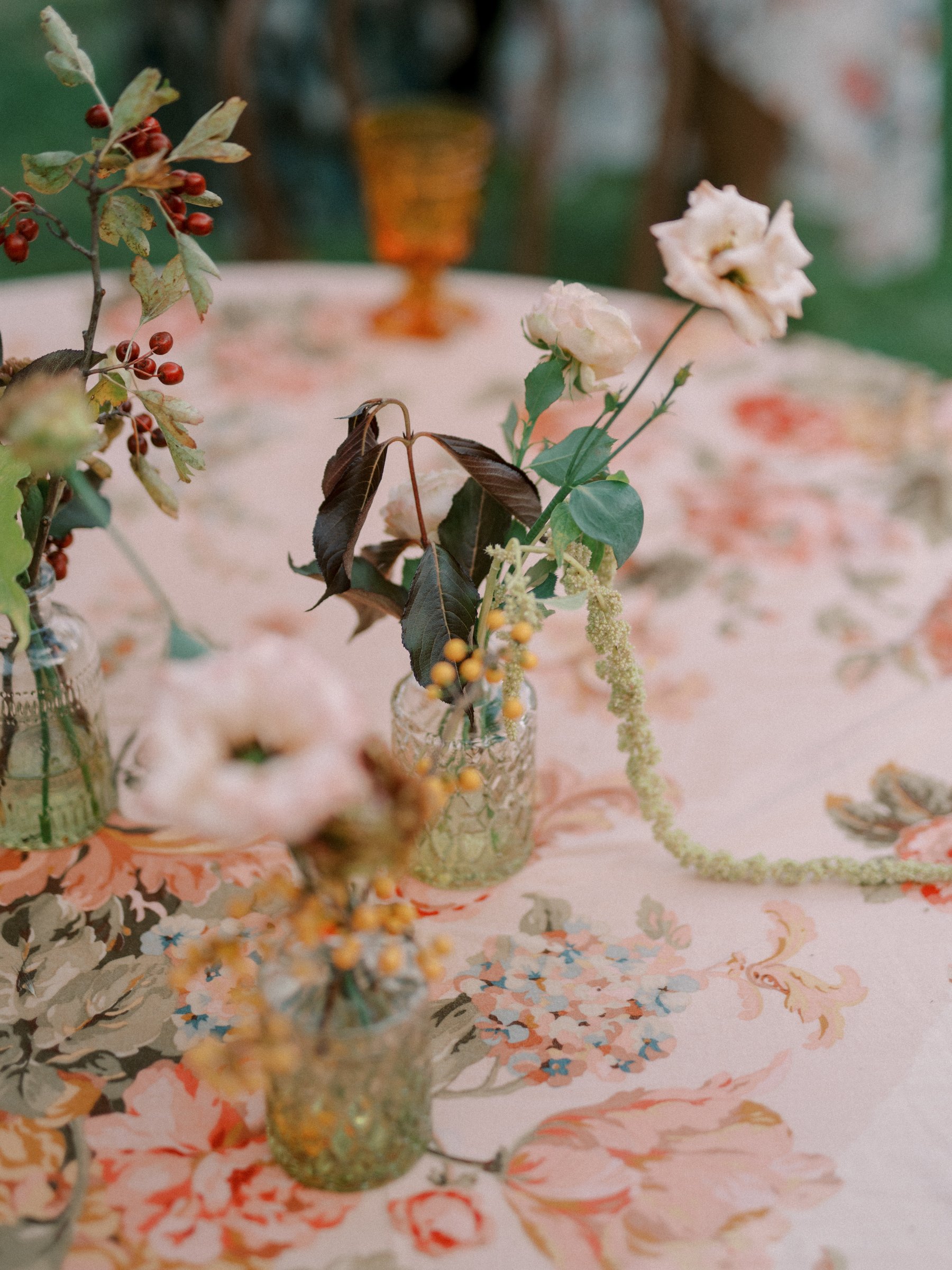 Authentic vintage sage green glass bud vases styled on an elegant outdoor wedding table with romantic florals, layered linens, and timeless garden-inspired décor.