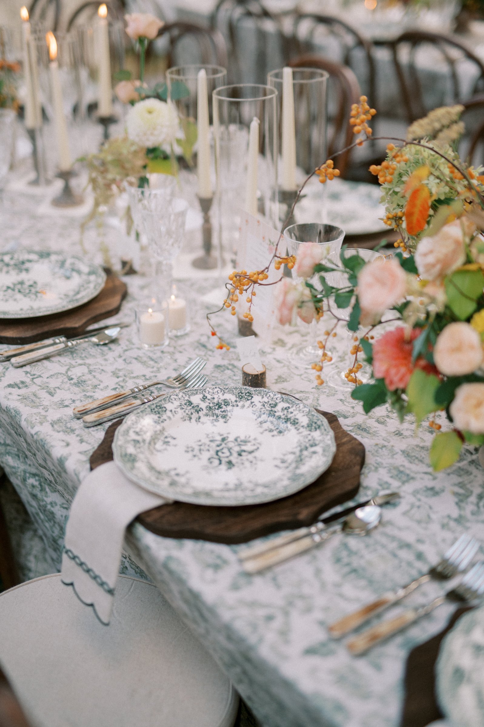 Acacia wood chargers styled beneath elegant dinnerware at a romantic wedding reception